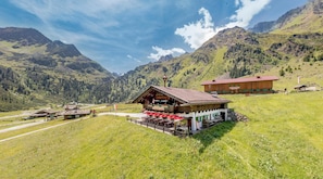 A mountain lodge with outdoor seating and a view of the surrounding mountains. - Pension Almrausch (Neustift Im Stubaital)