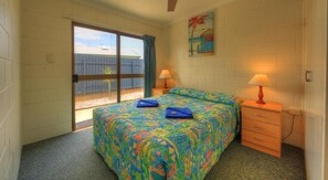 A bedroom with a bed, two bedside tables, a window, and a door leading to an outdoor area. - Sunlover Lodge (Kinka Beach)