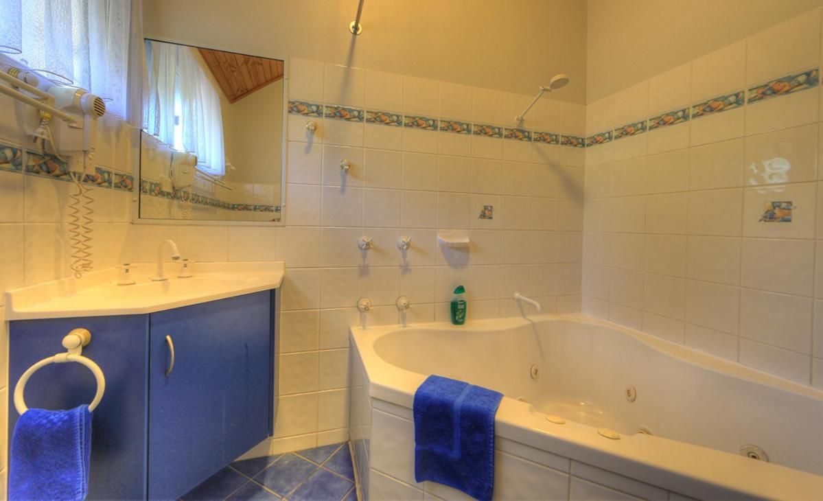 A bathroom with a bathtub, a sink, a mirror, and a towel ring.