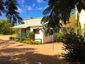 A single-story building with a covered porch, a sign indicating 'PARKING CABIN 7', and a clear blue sky. - Sunlover Lodge (Kinka Beach)