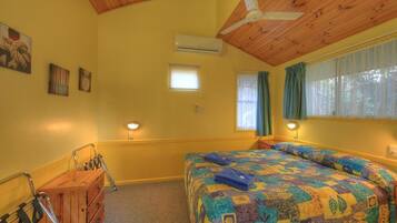A room with a bed, a wooden dresser, a ceiling fan, and a window with curtains.