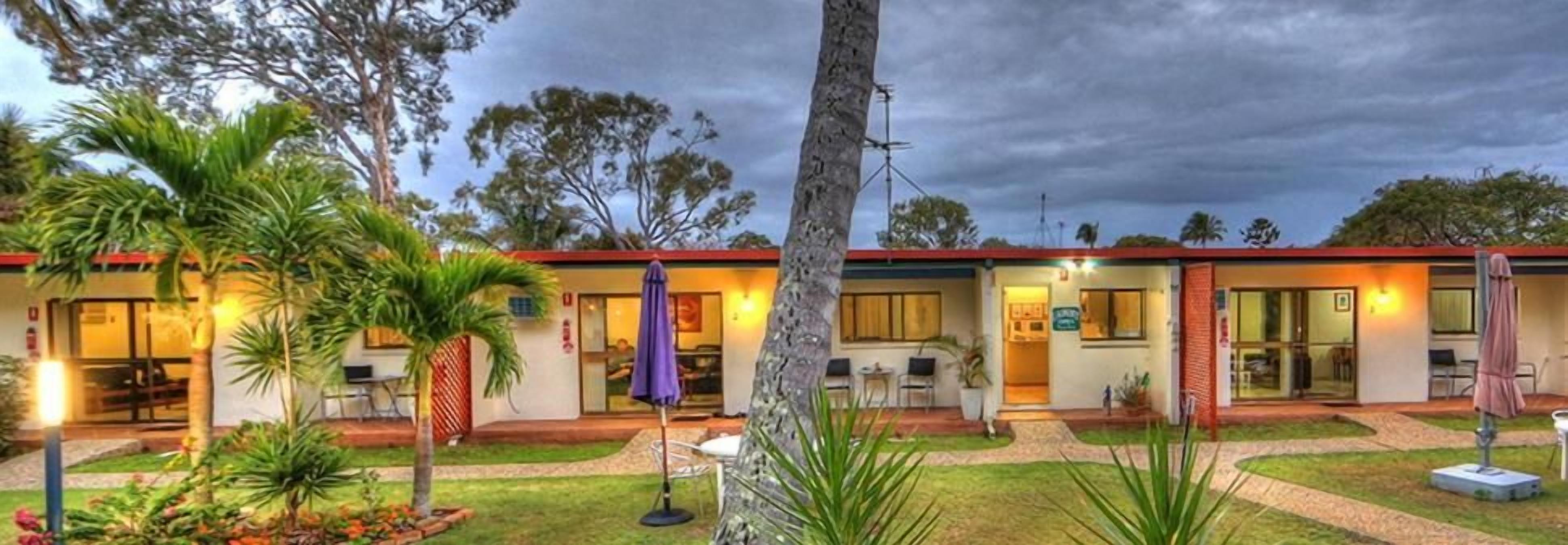A hotel with a two-story structure, outdoor seating, and a well-maintained garden.