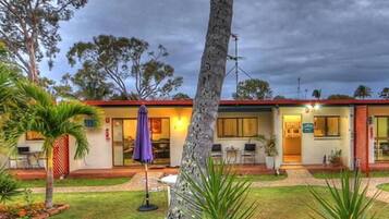 A hotel with a two-story structure, outdoor seating, and a well-maintained garden.