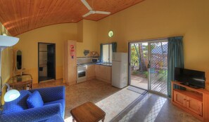A compact living space with a kitchenette, a sofa, a television, and a sliding glass door leading to an outdoor area. - Sunlover Lodge (Kinka Beach)