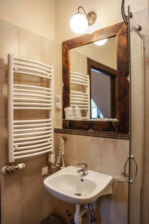 A bathroom with a white sink, a mirror with a wooden frame, and a towel rack. - Hotel Pod Kogutkiem (Sulkowice)