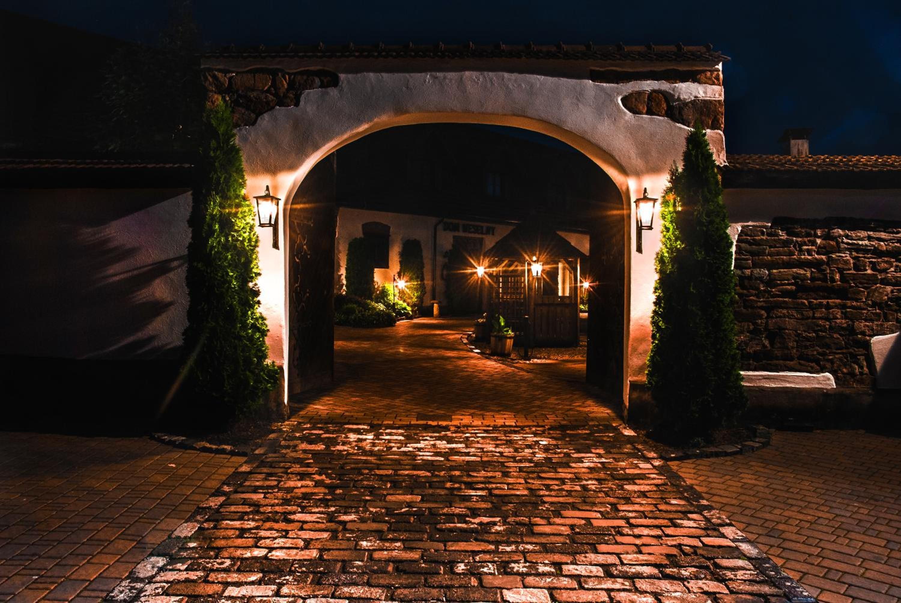 Una entrada en arc a un edifici, amb un camí empedrat que hi passa.