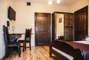 A room with a bed, a desk, a chair, and a television mounted on the wall. - Hotel Pod Kogutkiem (Sulkowice)