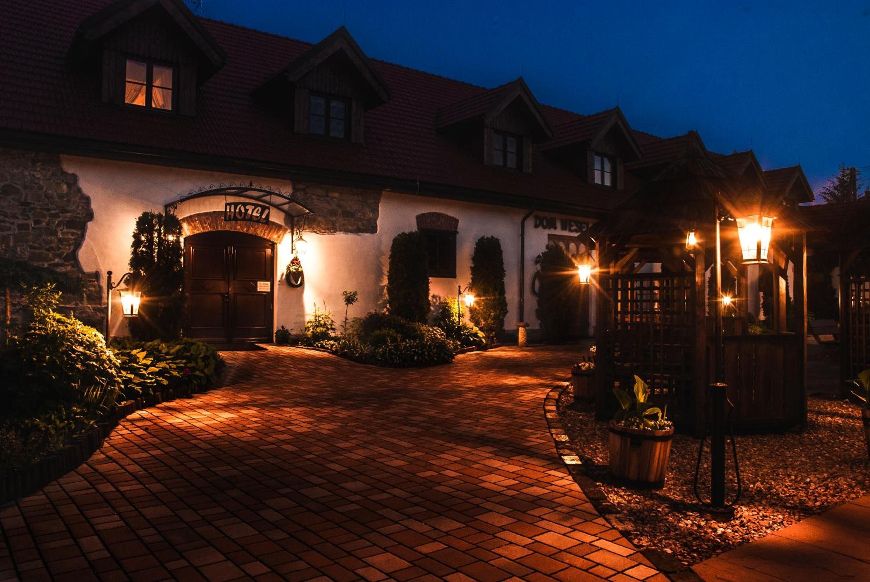 A hotel with a brick pathway leading to the entrance, a well-lit archway, and a sign indicating the hotel's name.