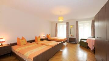 A hotel room with two beds, a sitting area, and a wardrobe.