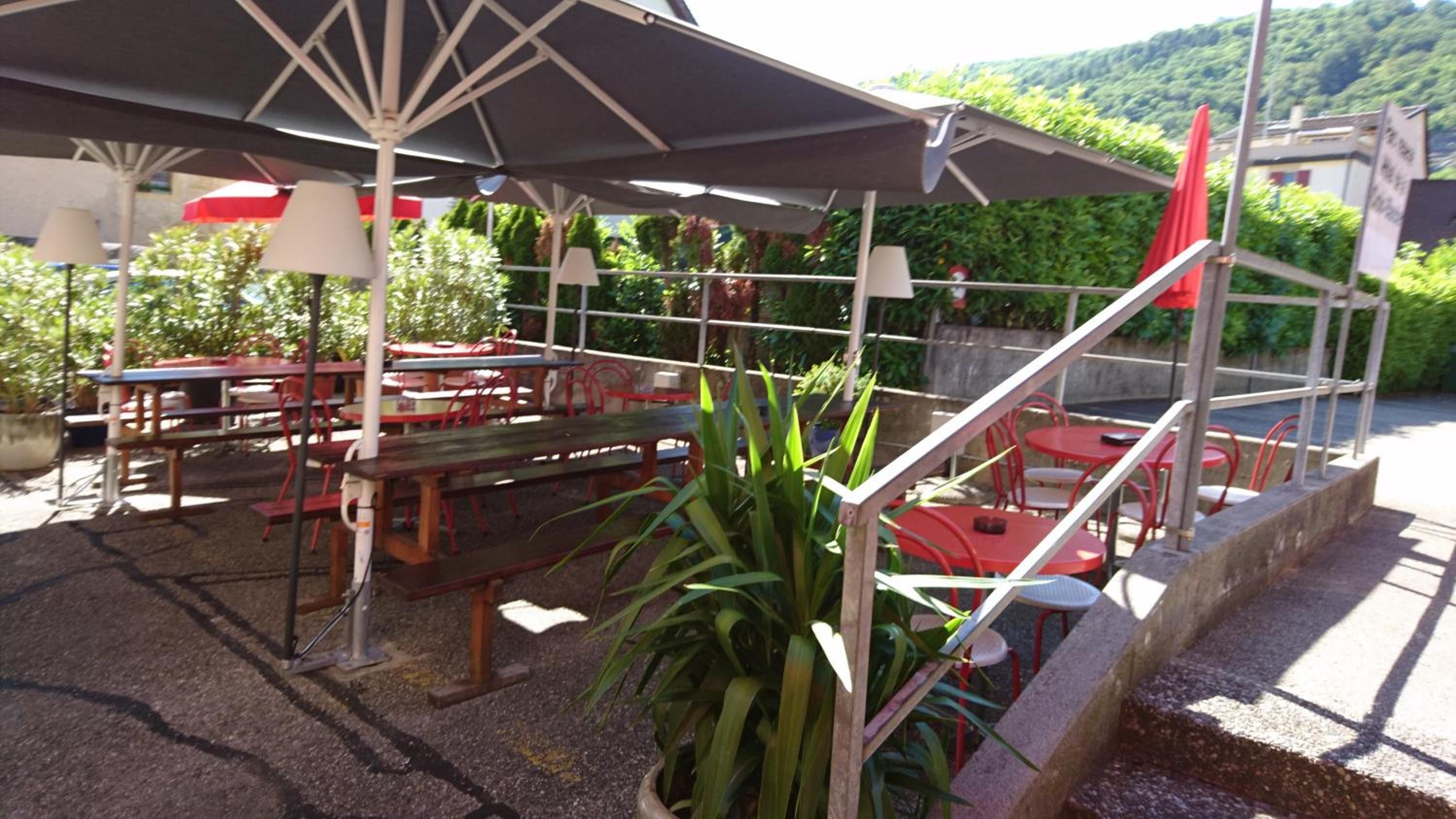 Un espacio al aire libre con mesas, sillas, sombrillas y plantas en macetas.