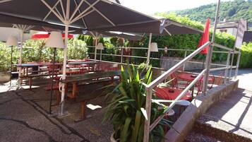 An outdoor seating area with tables and chairs, umbrellas, and potted plants.
