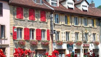 A hotel with multiple stories, red shutters, and flower boxes on the facade.