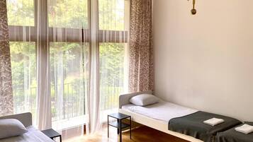 A room with two beds, a small table, a chair, and a chandelier.