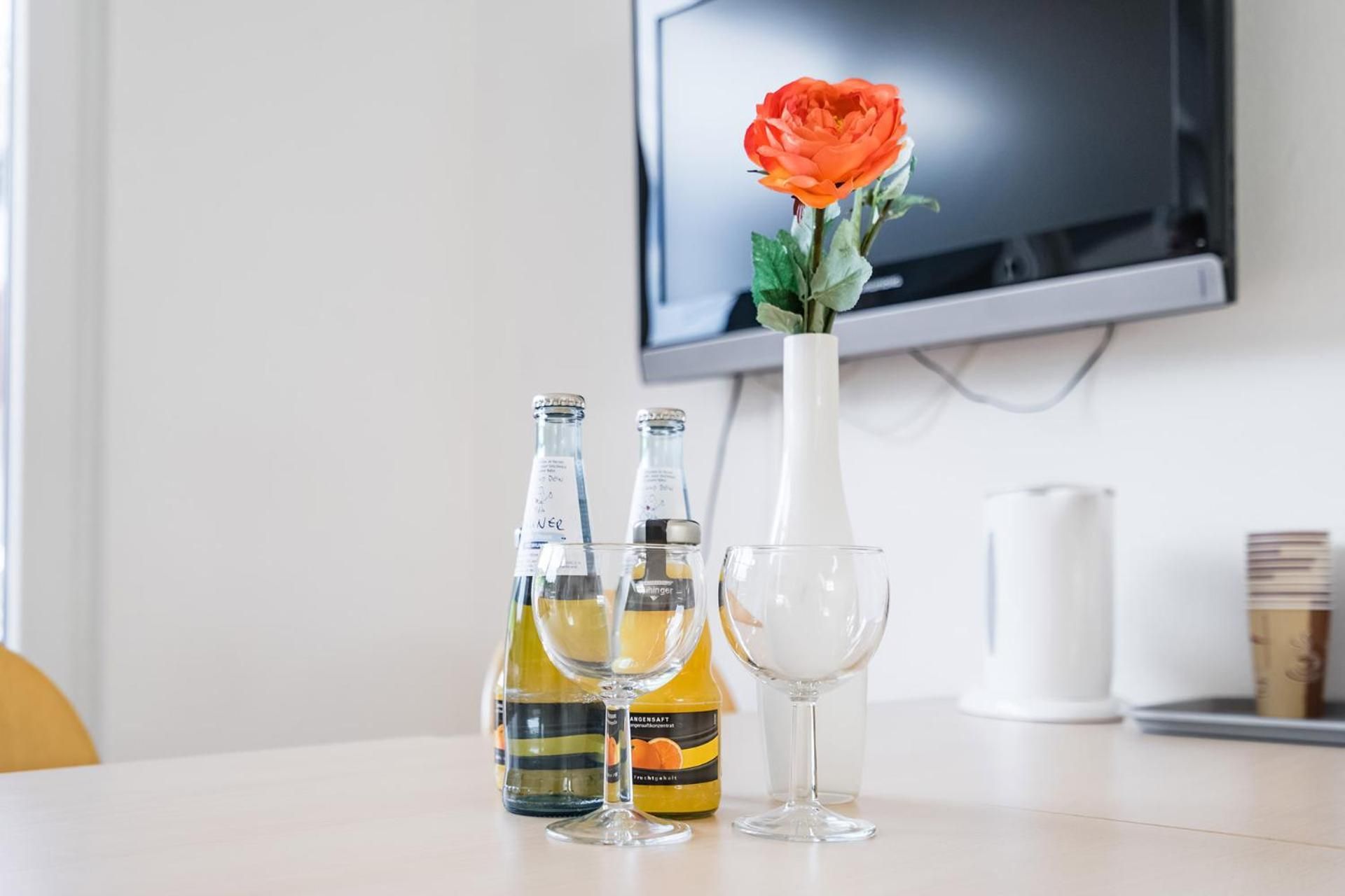 Ein Tisch mit zwei Flaschen, einem Glas und einer Vase mit einer Rose.