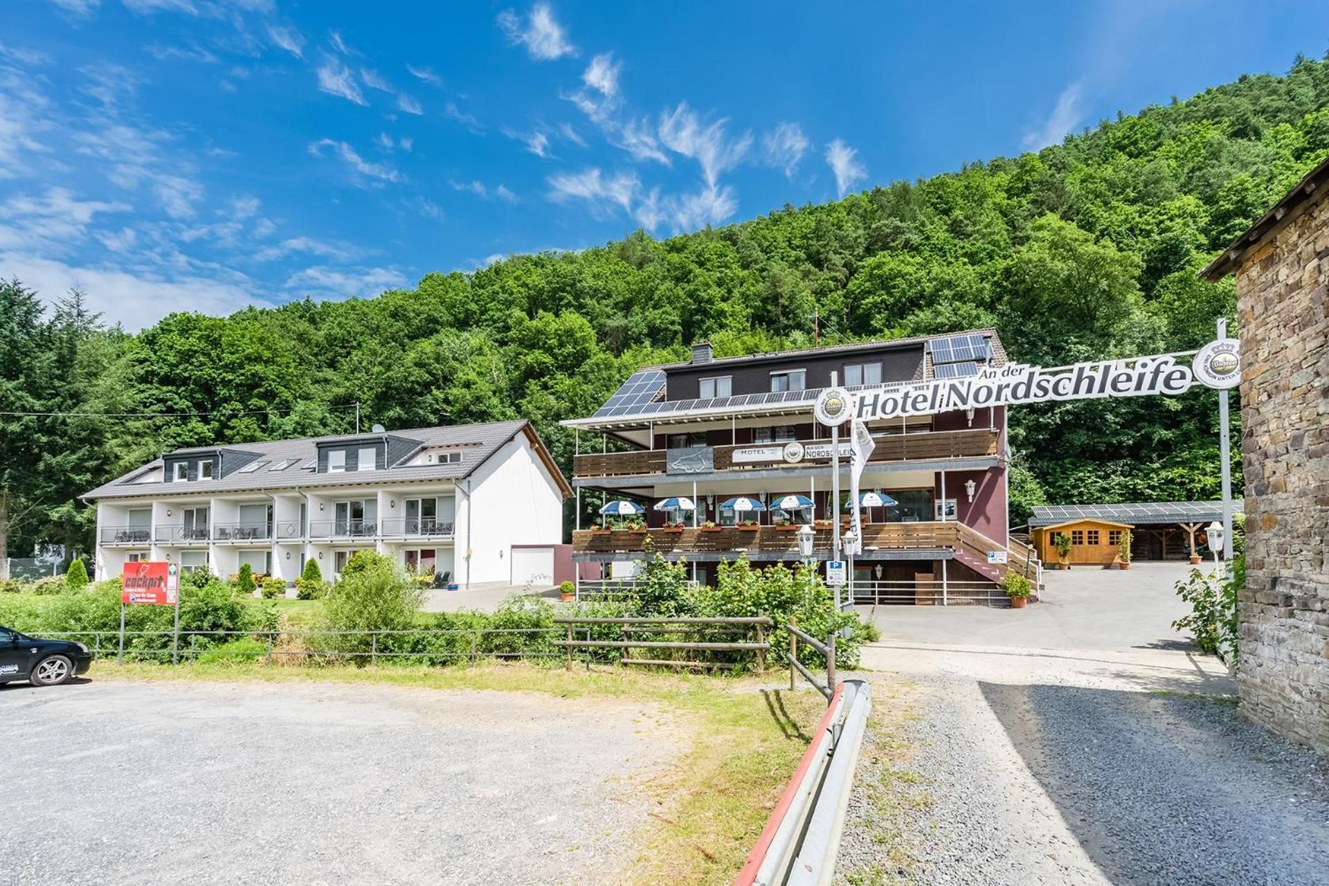 Un hotel con un cartel que dice 'Hotel Nordschleife' y un estacionamiento al frente.