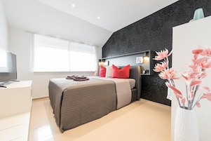 A modern bedroom with a bed, a desk, and a large window.