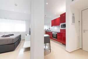 Un apartamento moderno con un dormitorio, kitchenette y comedor.