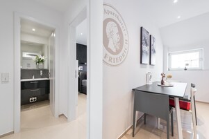 Una cocina moderna con comedor, un logotipo montado en la pared y un ventanal que proporciona luz natural.