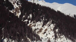 A snow-covered mountain with a cluster of wooden cabins. - Hotel Weisshorn (Goms)