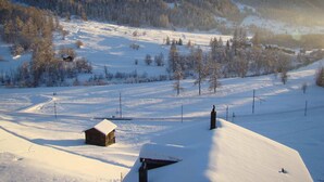 A snow-covered landscape with a cabin and a ski lift in the background. - Hotel Weisshorn (Goms)
