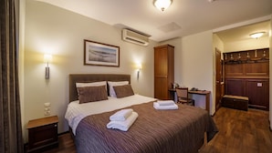 A hotel room with a large bed, a desk, a wardrobe, and an air conditioning unit. - Motel Panorama (Bubiai)