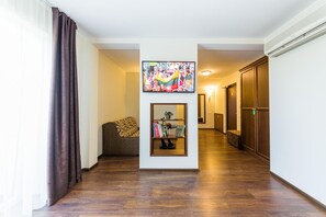 Un pasillo con suelo de madera, un sofá, una estantería y un cuadro en la pared.