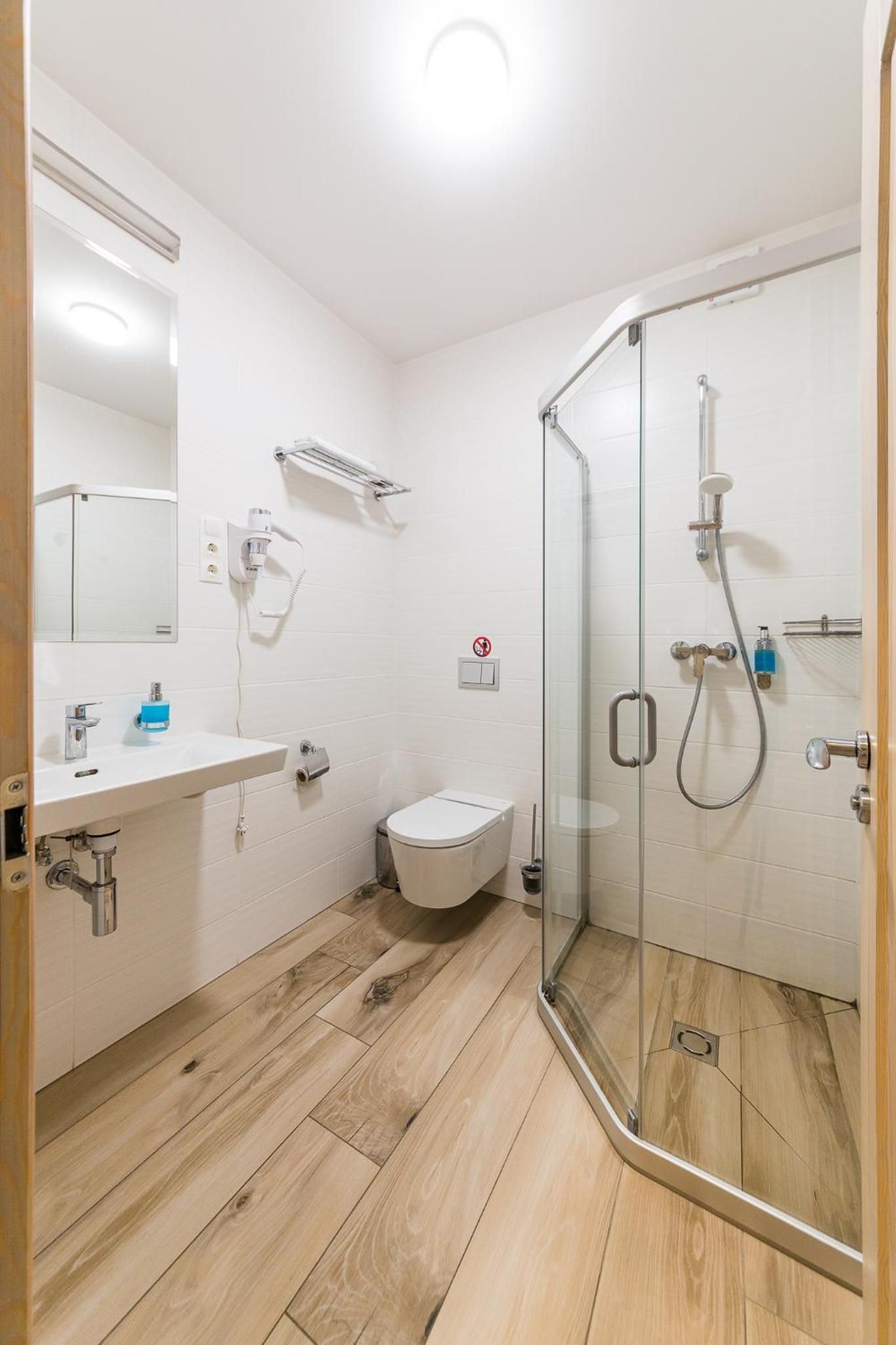 Ein modernes Badezimmer mit Duschkabine aus Glas, Toilette und Waschbecken mit Handtuchhalter.