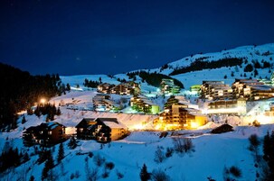 Un pueblo montañoso cubierto de nieve en la noche con edificios iluminados.