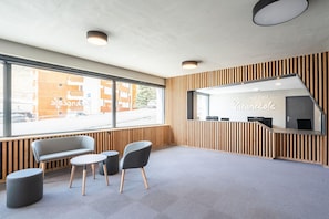 Uma área de recepção moderna com um banco, duas cadeiras, uma mesa pequena e um balcão de recepção.