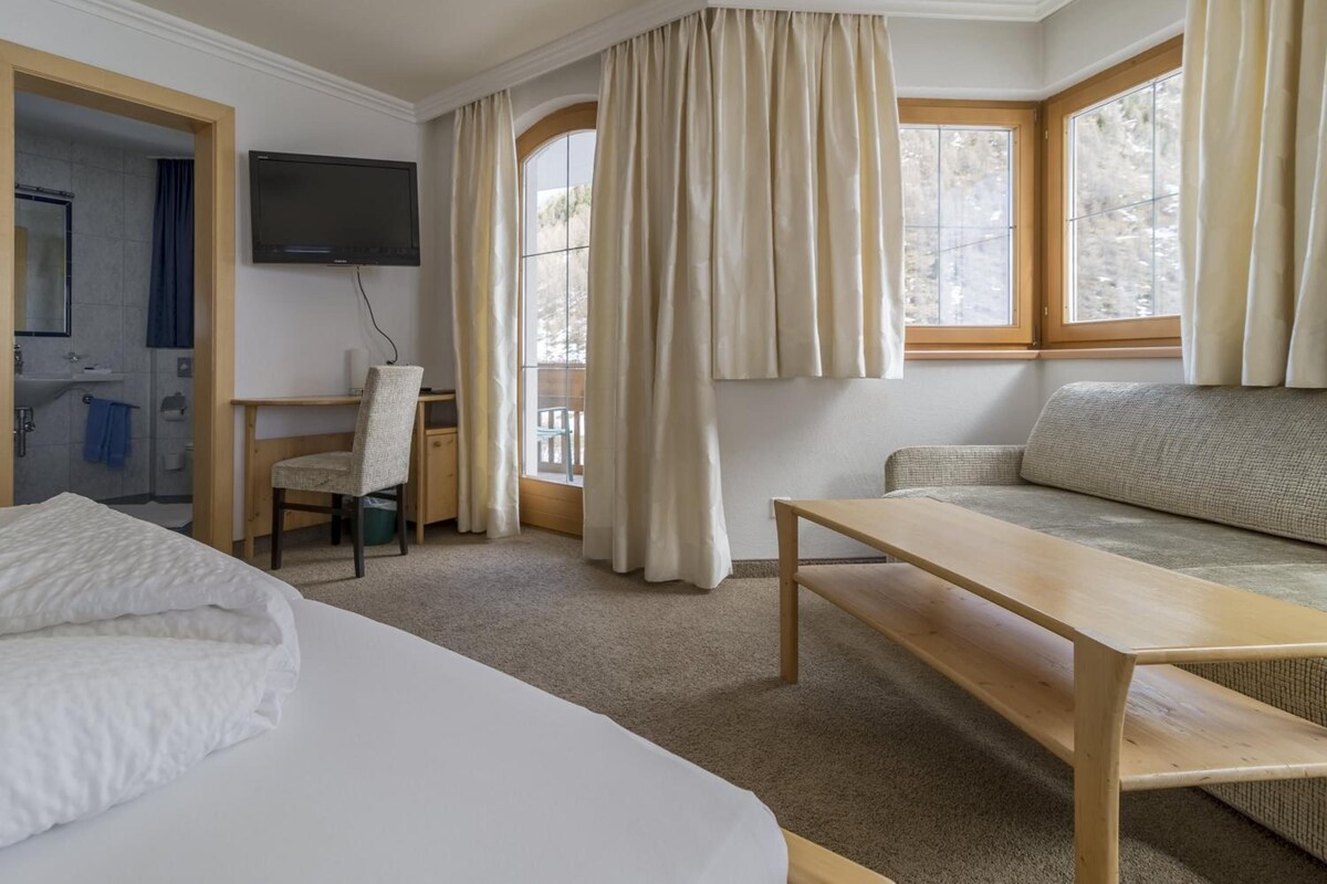 Una habitación de hotel con una cama, un escritorio, una silla, un sofá y un televisor.