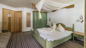 Ein Zimmer mit einem Bett, einem grünen Kleiderschrank, einer Holztür und einem gemusterten Teppich.