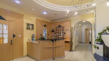 A reception area with a wooden reception desk, a framed picture on the wall, and a plant in the corner.