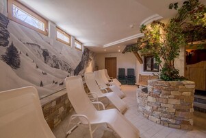 Un cuarto de spa con sillones reclinables, una pared de piedra y un mural de un paisaje montañoso.