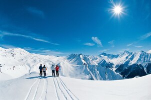 A snowy mountain landscape with a clear sky and a bright sun.