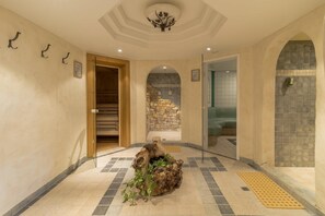Un pasillo con una escultura de madera, suelo de baldosas y una pared de piedra.
