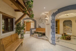 A hotel lobby with a wooden bench, a stone wall, and a staircase.