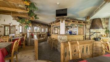 A rustic interior with wooden furniture, stone walls, and a bar area.