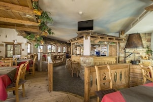 Un interior rústico con muebles de madera, paredes de piedra y una zona de bar.