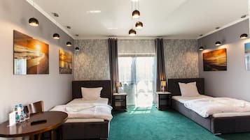 A hotel room with two beds, a desk, and artwork on the walls.