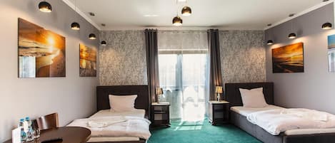 A hotel room with two beds, a desk, and artwork on the walls.
