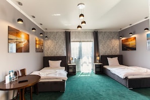A hotel room with two beds, a desk, and artwork on the walls.