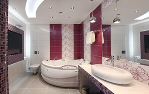 A modern bathroom with a curved bathtub, a large mirror, and a vanity with a sink.