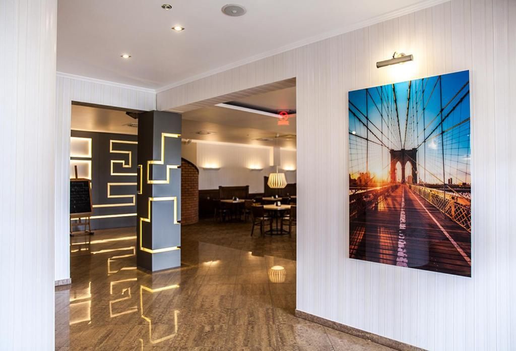 A modern interior with a geometric light installation, a dining area, and a large framed picture of a bridge.