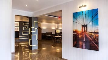 A modern interior with a geometric light installation, a dining area, and a large framed picture of a bridge.
