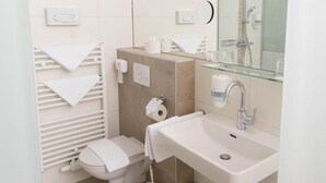Un baño moderno con inodoro, lavamanos y ducha.