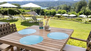 Una mesa de madera con dos individuales azules, un letrero con un código QR y un florero con flores secas.