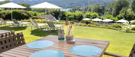 A wooden table with two blue placemats, a QR code sign, and a vase with dried flowers.