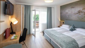 Una habitación de hotel con cama, escritorio con silla, televisión y un cuadro en la pared.