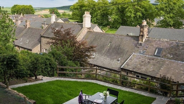 A residential area with multiple houses, a grassy lawn, and a wooden fence. - Chatton Cottage (Alnwick)