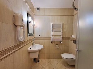 A bathroom with a sink, toilet, towel rack, and hand dryer.